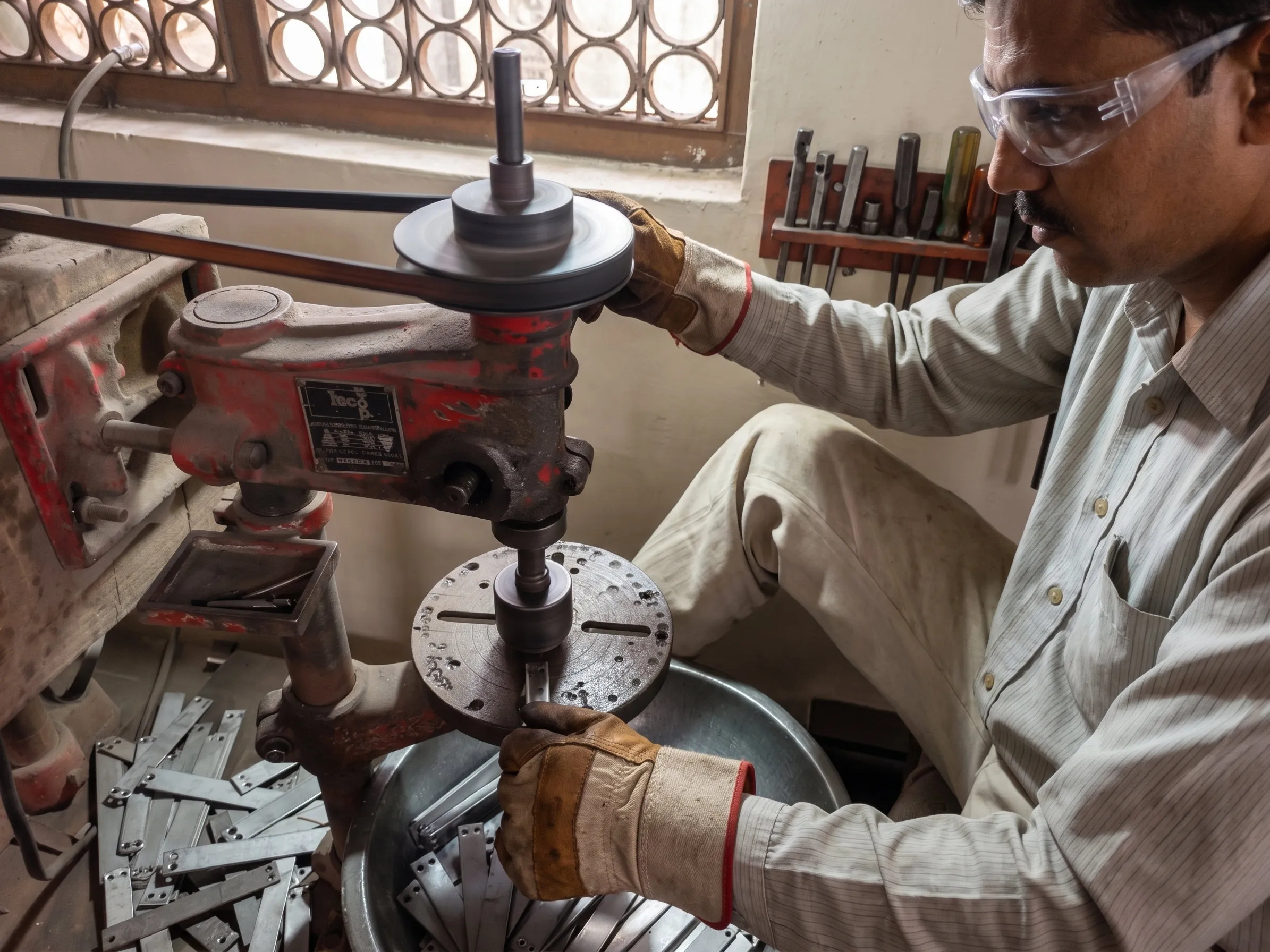 Operator drilling hardware components on a drill machine at the Leena Hardware factory in Aligarh
